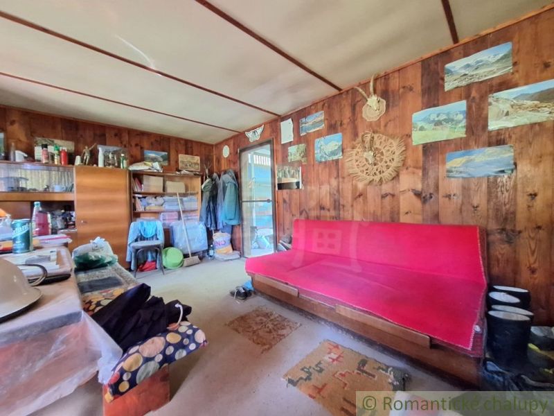 The interior of a cabin with wooden decor, a sofa, and decorations on the walls.
