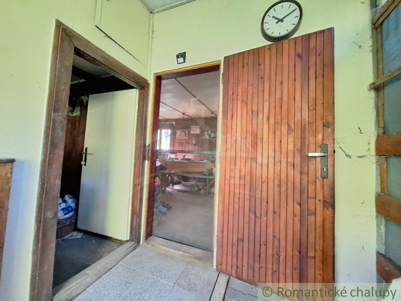 The interior of the cabin features wooden doors, a clock, and a tiled floor.