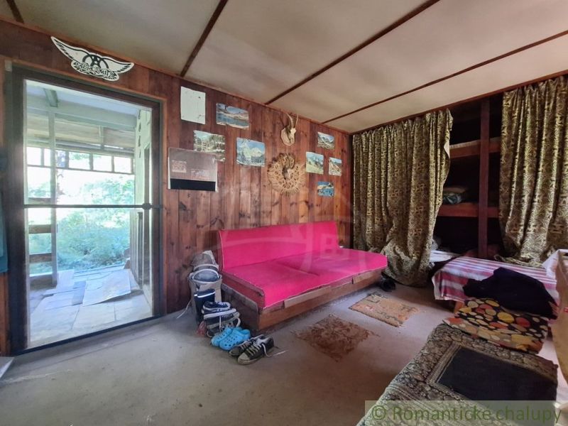 Interior of a cabin with wooden walls, a pink sofa, and decorative curtains.
