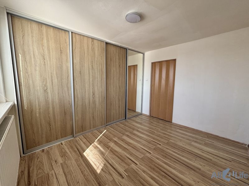 A room in a 3-room apartment with a wooden decor floor and a built-in wardrobe.
