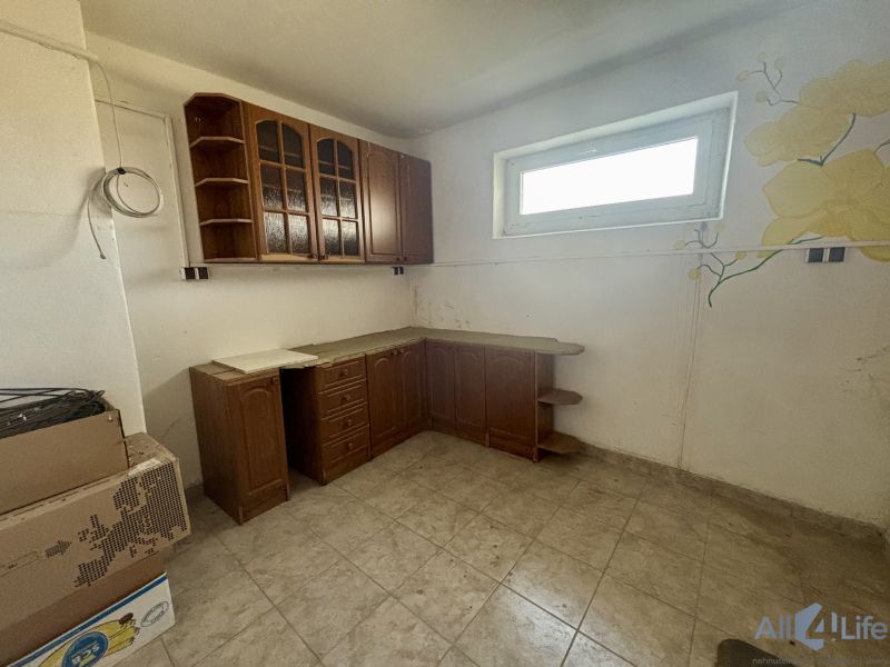 A kitchen unit in a 3-room apartment with a floral pattern on the wall, tiled floor.