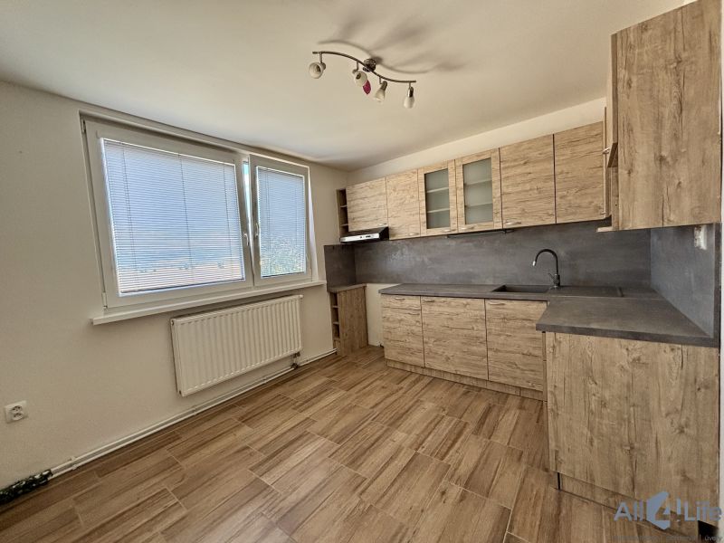 A kitchen in a 3-room apartment with a wooden decor floor and large windows.