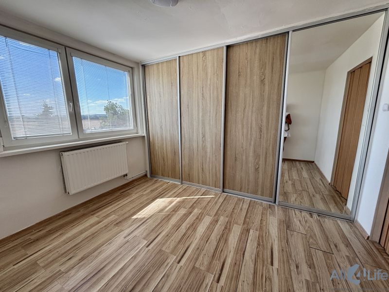 A room with a wooden decor floor and a built-in wardrobe in a 3-room apartment.