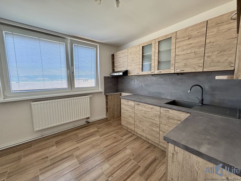 The kitchen of a 3-room apartment with cabinets featuring a wooden decor and large windows.