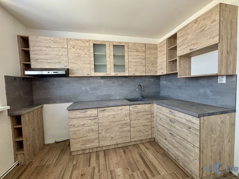 A kitchen with wooden decor and a dark countertop in a 3-room apartment.