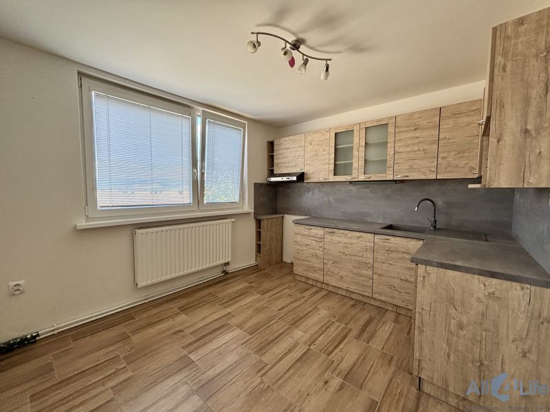 A kitchen with a wooden decor in a 3-room apartment with a large window and a bright space.