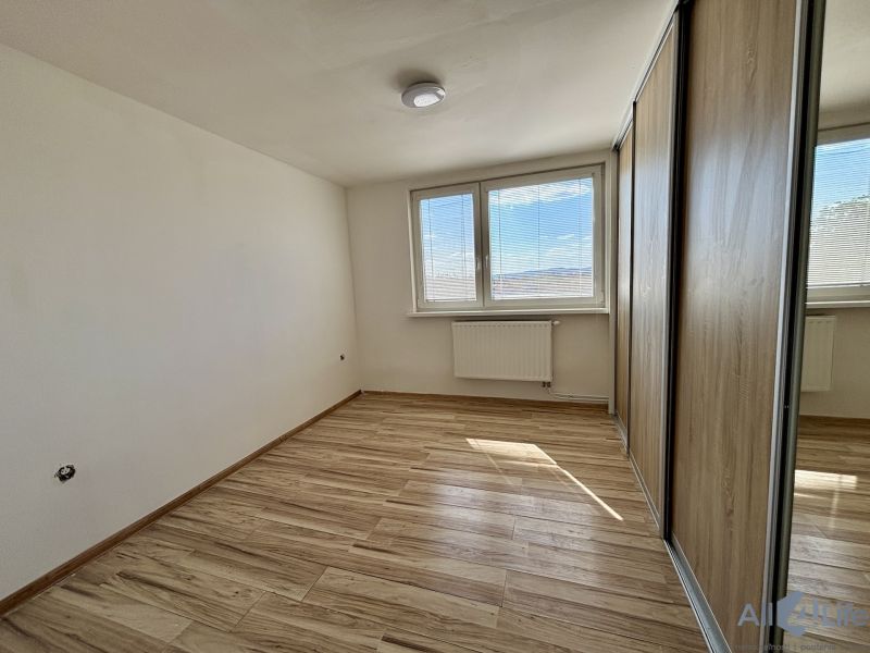 A room with a wooden decor floor and a built-in wardrobe in a 3-room apartment.
