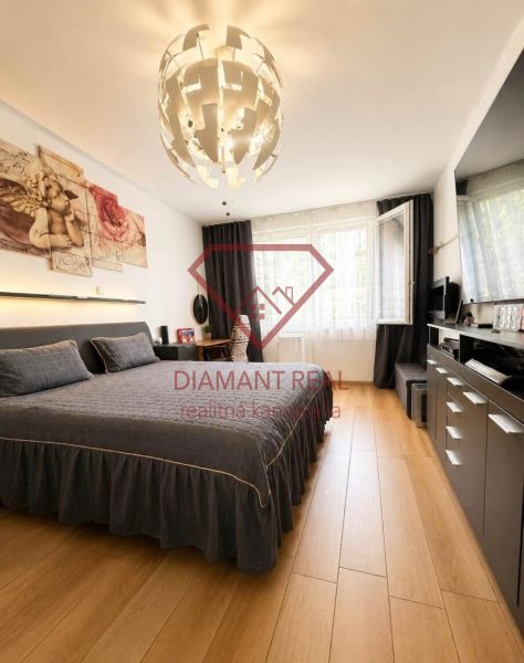 Bedroom in a 2-room apartment with wood-patterned flooring and a stylish chandelier.