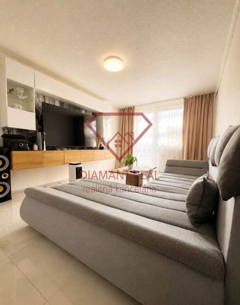 Living room in a two-room apartment with a large sofa and a TV on the wall.