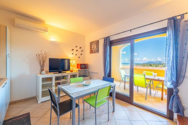 Recreational apartment with light flooring, dining table, and view of Sardinia.