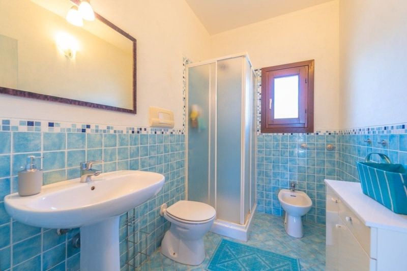 A bathroom in a holiday apartment with blue tiles and a shower enclosure.