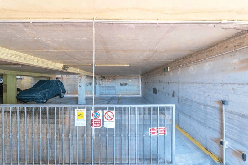 Underground garage of a holiday apartment in Sardinia with a parked car and a security gate.
