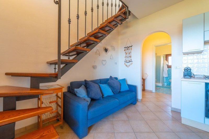 Blue sofa and staircase in a vacation apartment with wood-patterned flooring.