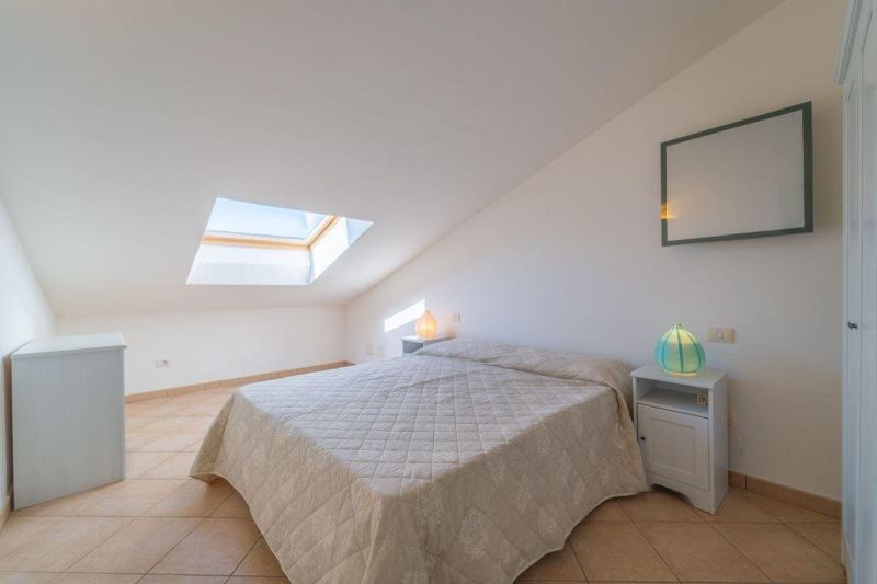 A bright attic bedroom space with a double bed and a skylight.