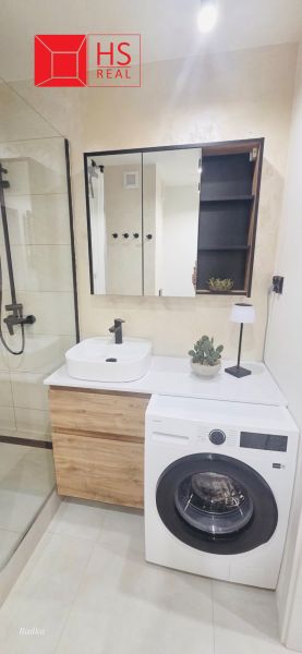 A bathroom in a 3-room apartment with a washing machine, mirror, and shower.