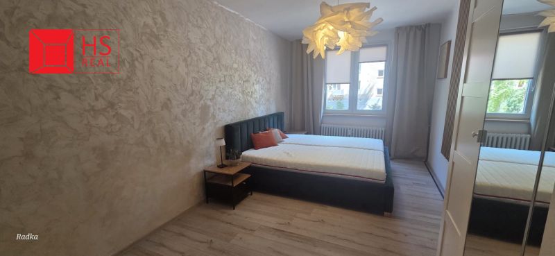 A bedroom with a bed, curtains, and a wooden decor floor in a 3-room apartment.
