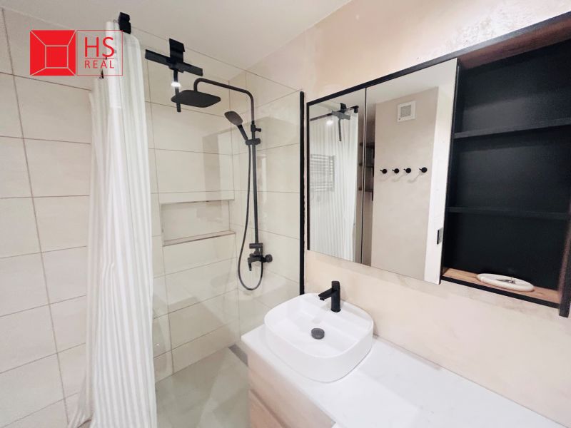 Bathroom with black faucet and shower, mirrored cabinet, modern tiles, 3-room apartment.