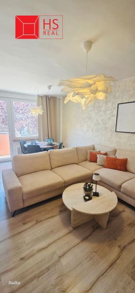 A living room in a three-room apartment with a large sofa and a floor with a wooden decor.