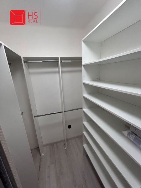 Wardrobe with shelves and rods in a 3-room apartment, floor with wood decor.