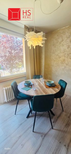 Dining area in a 3-room apartment with a round table and green chairs.