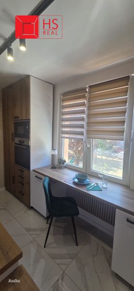 A kitchen in a 3-room apartment with a dining counter, Christmas blinds, and marble flooring.