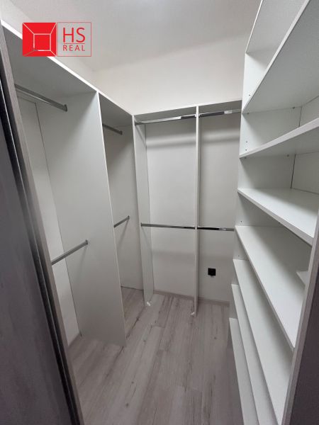 A wardrobe in a 3-room apartment with shelves and storage spaces, flooring with a wood decor.