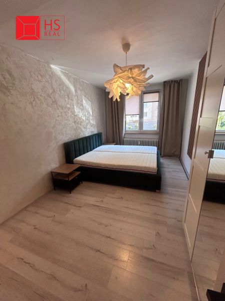 Bedroom in a 3-room apartment with a wooden decor floor and a stylish light fixture.