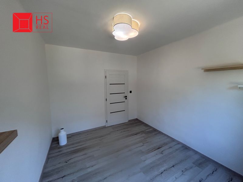 A room with a wooden decor floor and white walls in a 3-room apartment.