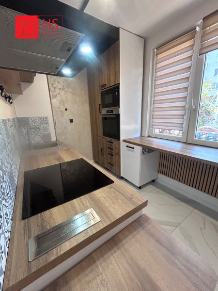 A kitchen with built-in appliances and a wooden decor floor in a 3-room apartment.