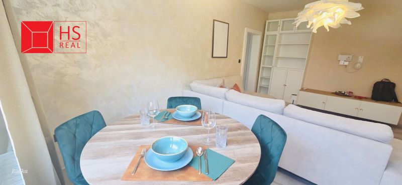 A dining table with place settings, behind it a sofa and a bookcase in a 3-room apartment.