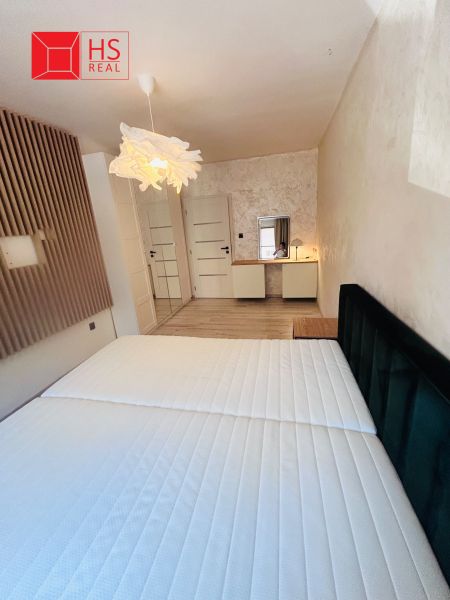 A bright bedroom in a three-room apartment with a wooden decor floor and a wardrobe.