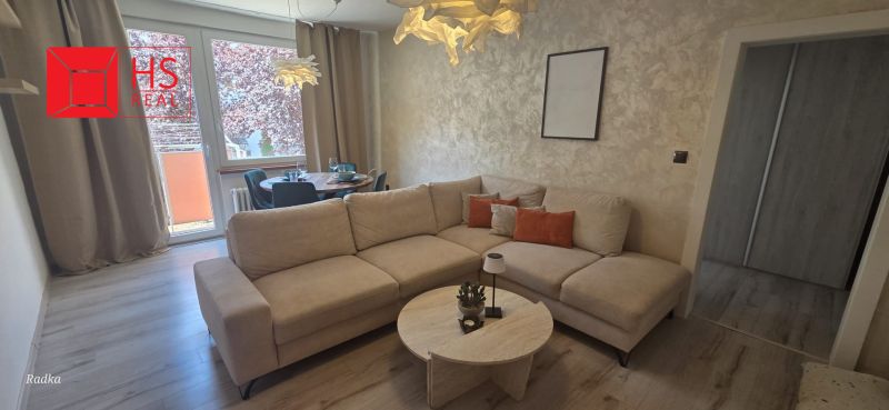 Comfortable sofa, dining table, wooden decor flooring in a 3-room apartment.