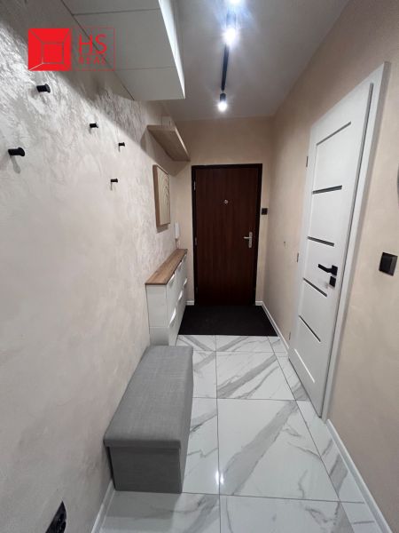 A hallway with light tiles and a bench in a 3-room apartment.