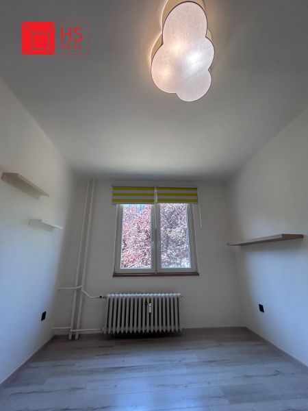 A room in a 3-room apartment with a wooden decor floor, light, and shelves.