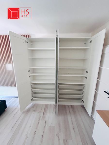 White built-in wardrobe with open doors and a wooden decor floor in a 3-room apartment.