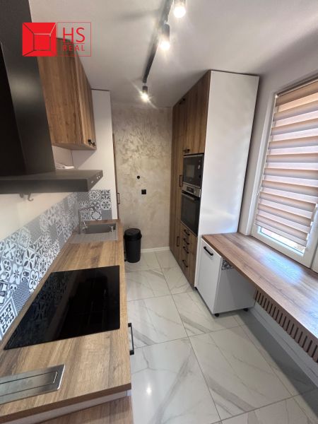 A kitchen with a wood-patterned floor, furnishings, and modern appliances in a 3-room apartment.