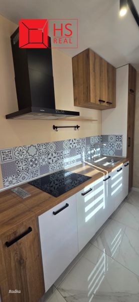 A kitchen with white cabinets, a wooden decor floor, decorative tiles.