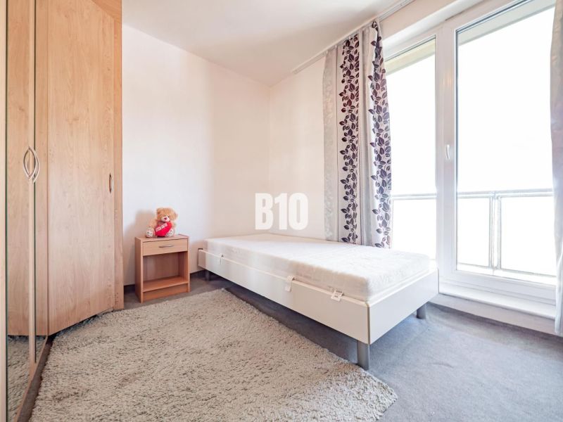 A bedroom with simple furnishings, a single bed, and large windows in a 3-room apartment.
