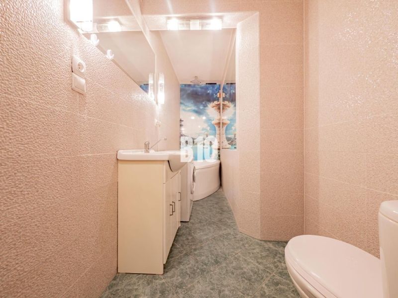 A bathroom with a bathtub and tiles in a 3-room apartment, light tones and a large mirror.