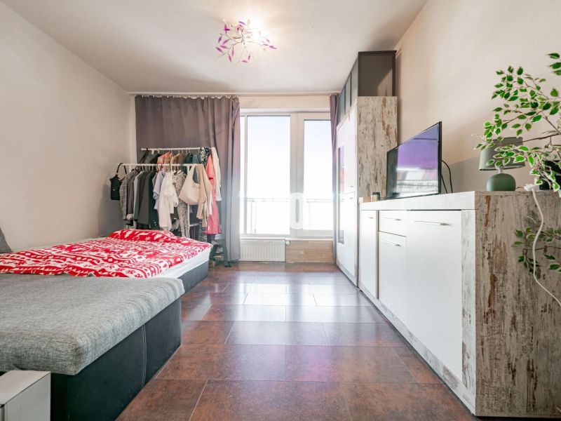 Living room of a three-room apartment with a wooden decor floor and a sofa.