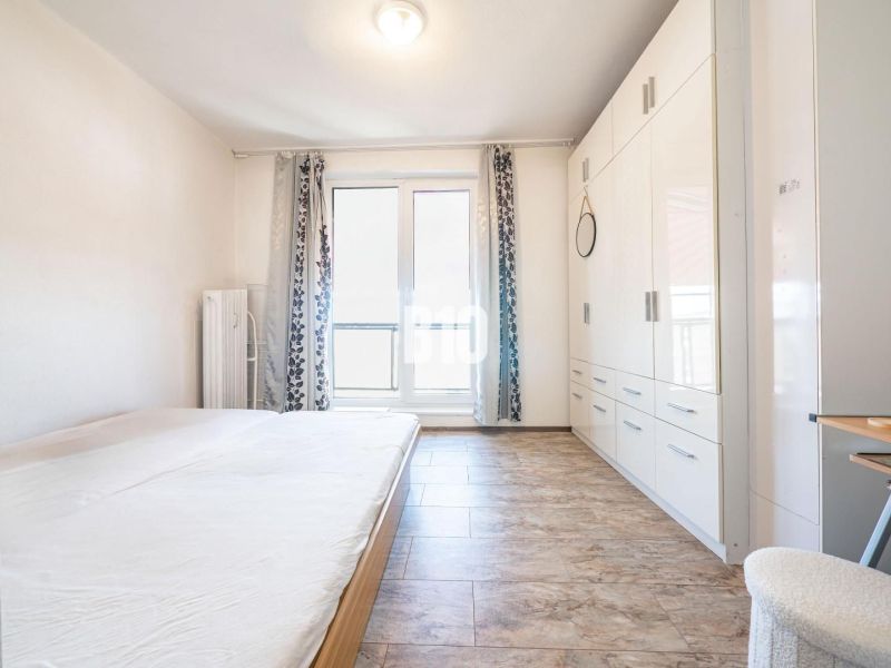 A bright bedroom in a 3-room apartment with a wooden decor floor and a built-in wardrobe.