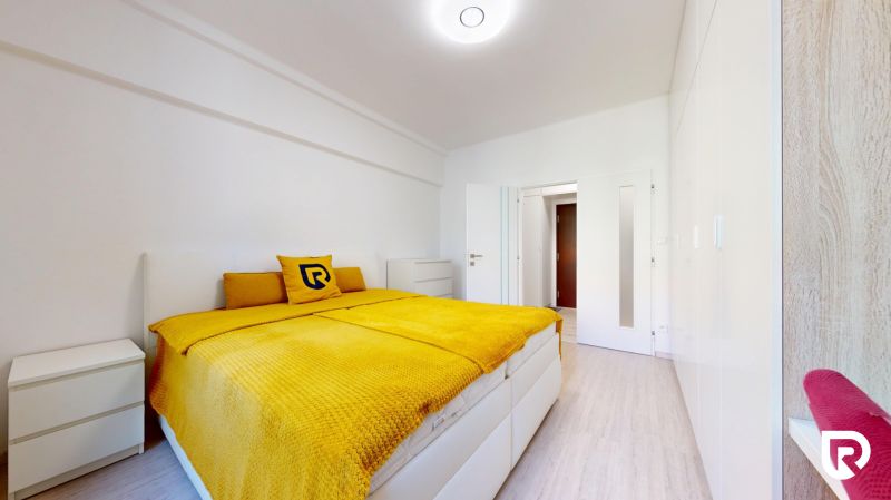 Bedroom in a 2-room apartment with a bed and white furniture, floor with wooden decor.