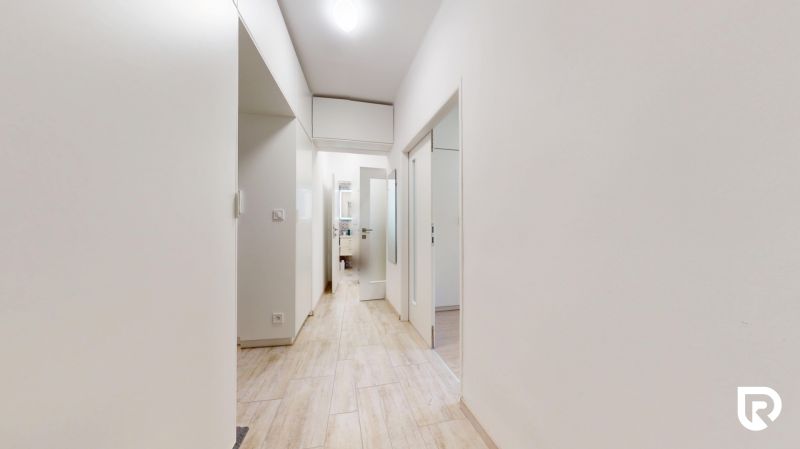 A bright hallway with white walls and a wooden decor floor in a 2-room apartment.