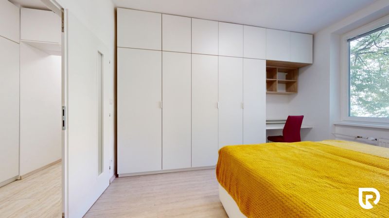 A bedroom in a two-room apartment with white wardrobes and a yellow bedspread.