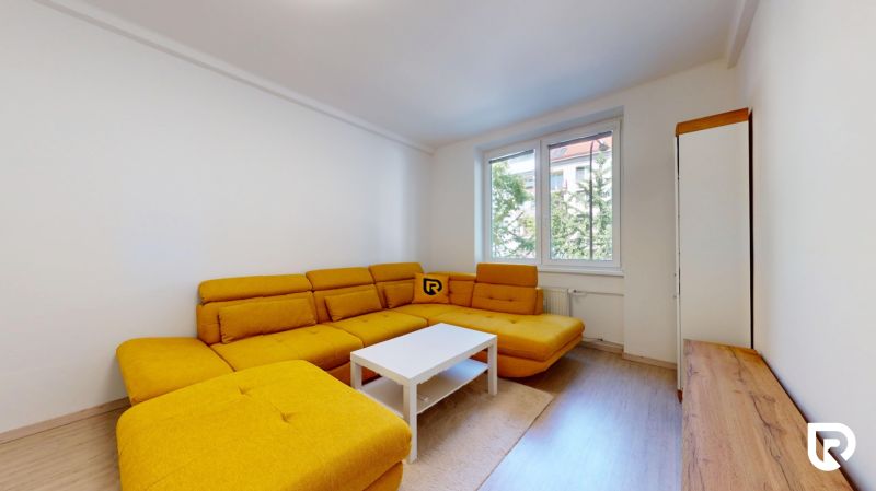 Living room with a yellow sofa, white coffee table, and wood-patterned flooring.