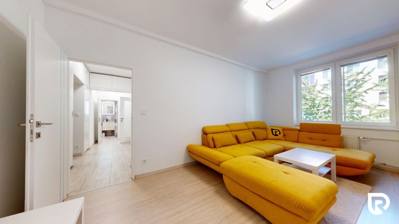 A living room with a striking yellow sofa and a wooden-patterned floor in a two-room apartment.