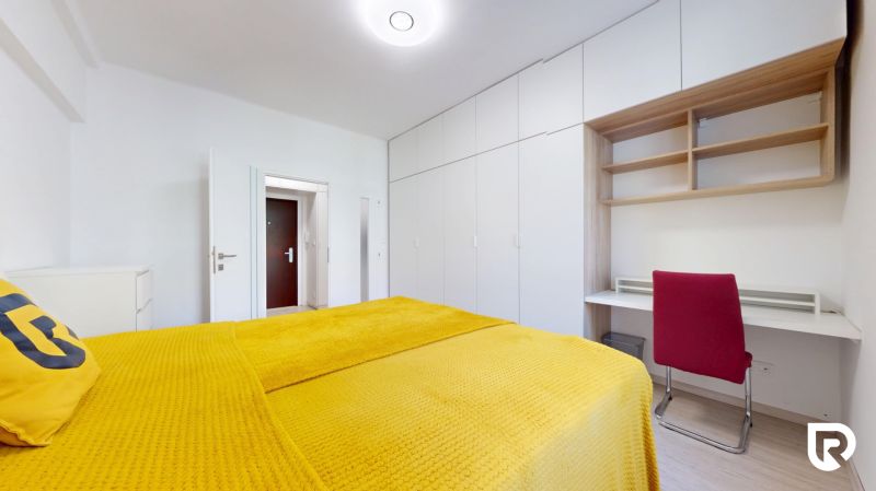 Bedroom in a two-room apartment with a bed and a built-in wardrobe, floor with wood decor.