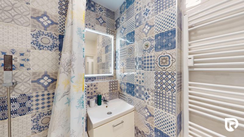 A bathroom with colorful tiles in a 2-room apartment offers an original design.