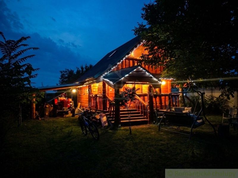 A family house in Lehota with wooden paneling illuminated by lights, garden swing.