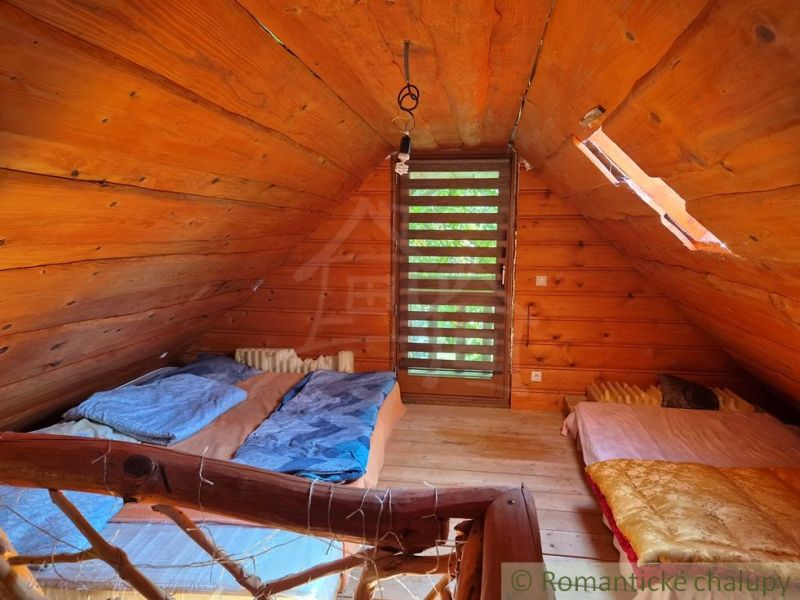 An attic room in a family house with wooden paneling and two beds.